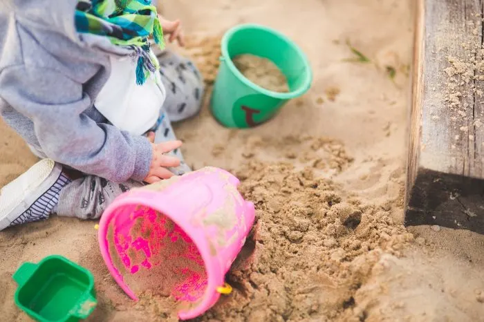 Child playing with buckets in the sandpit