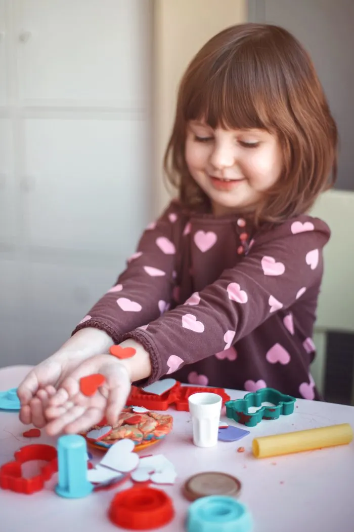 Child using playdough cutters to make shapes