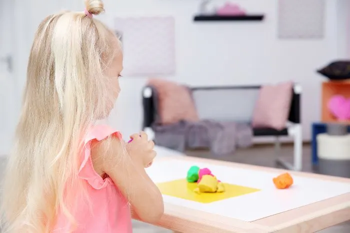 Girl playing with playdough at the table