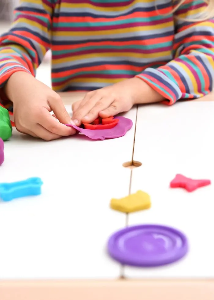 Young child moulding playdough with shapes