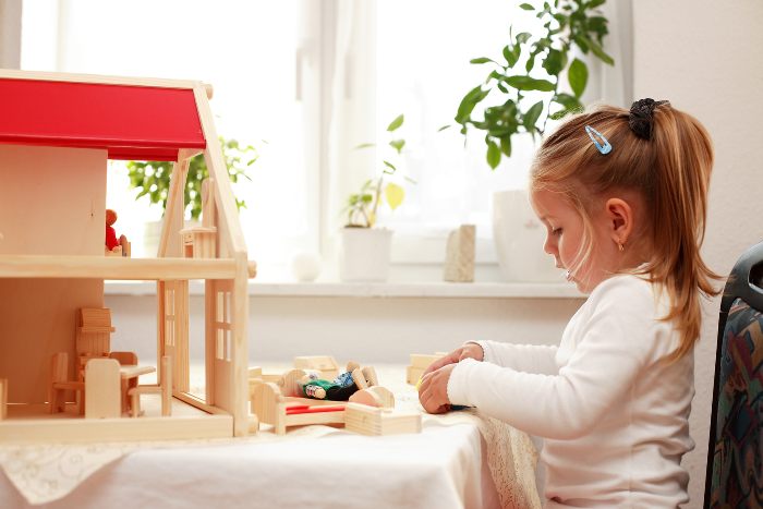 Child engaged in free play with her doll's house