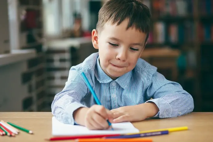 Boy sitting a a desk, drawing