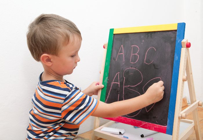 Child writing letters on a blackboard