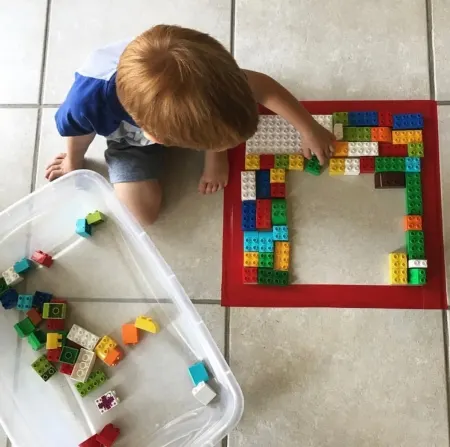 Child placing Lego in a square