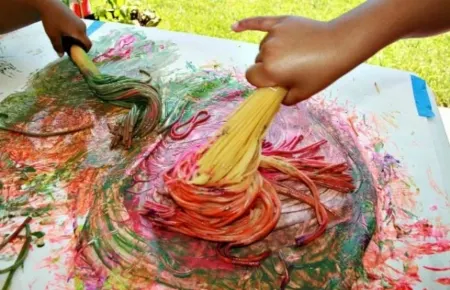 Preschool children painting with spaghetti 