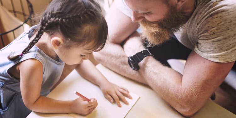 Father watching daughter draw a picture