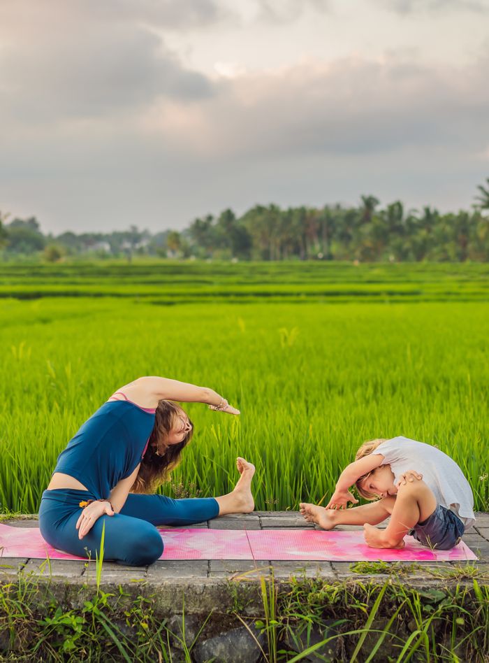 Child doing yoga with mother and leaning across the body
