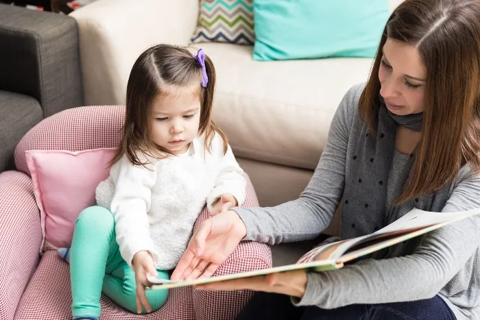 Child reading a book with mother