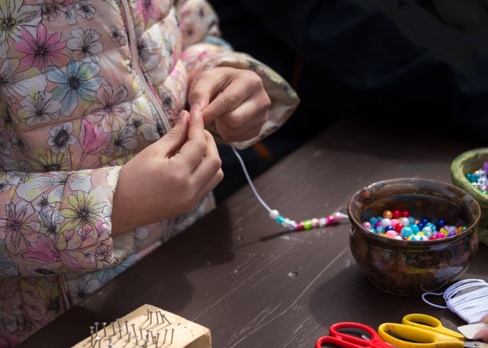 Child making a beaded necklace