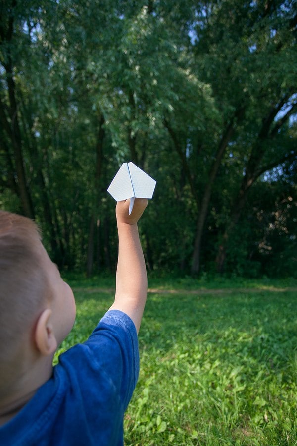 Child flying a paper airplane