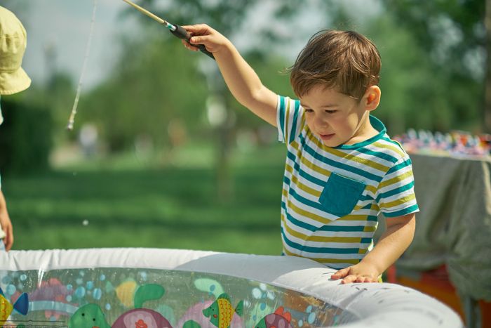 Child playing fishing game in an inflatable pool