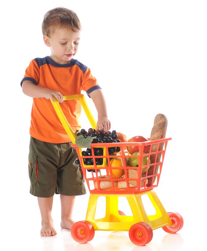 Child pushing a play trolley with groceries