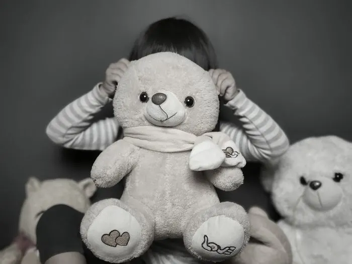 Girl hiding behind teddy bear