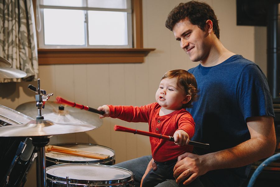 Father playing the drums with toddler