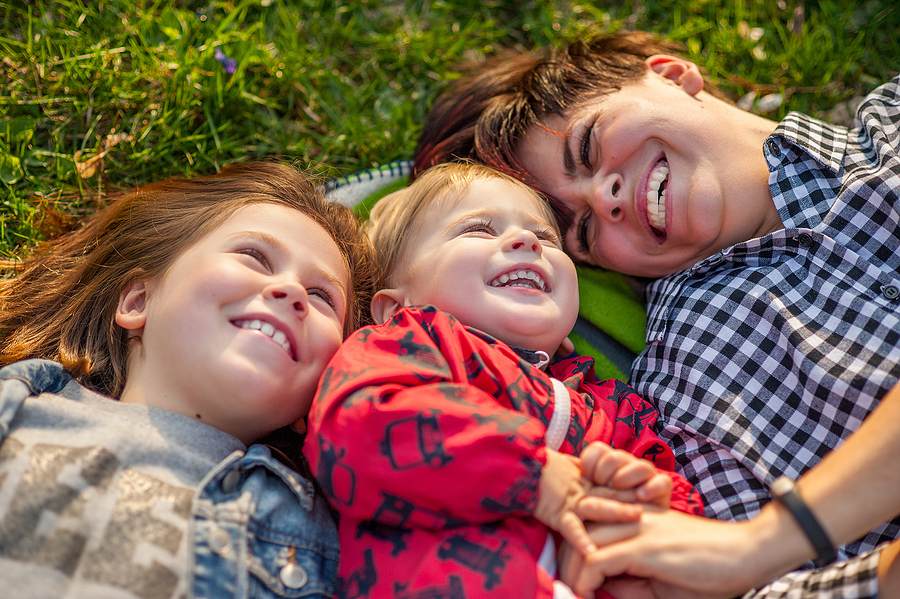 Mother and two children lying on grass together