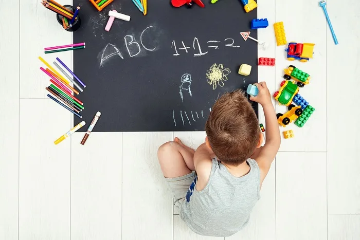 kid drawing numbers and letters with chalk
