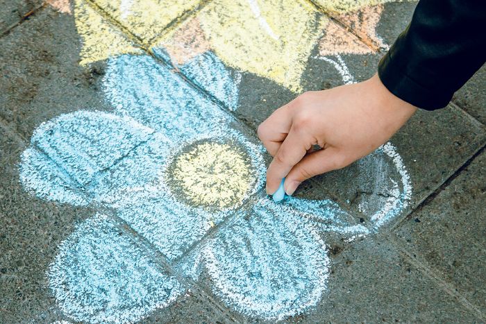 Child hand draws a chalk flower