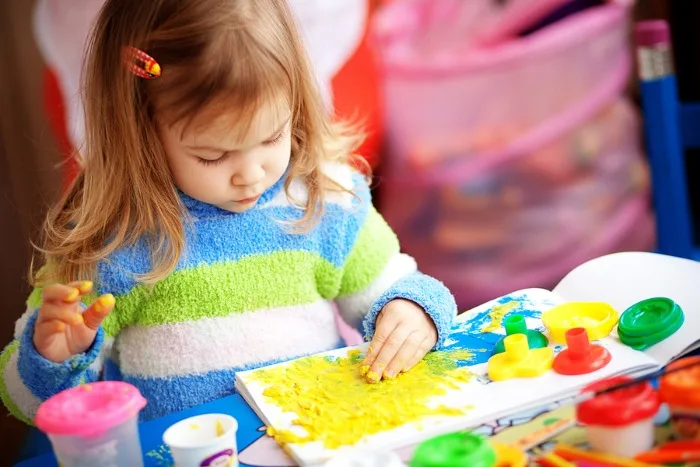 Young girl finger painting on paper