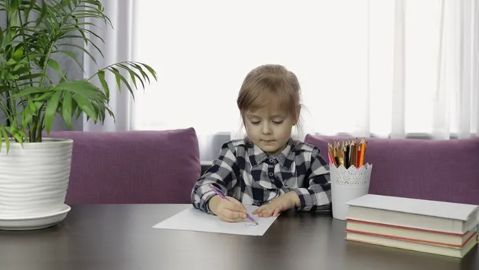 Child drawing on paper at a desk