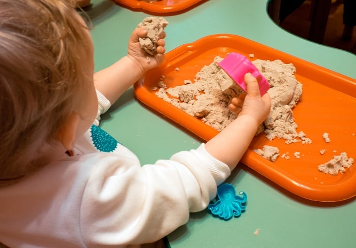 Toddler playing with sand on a tray