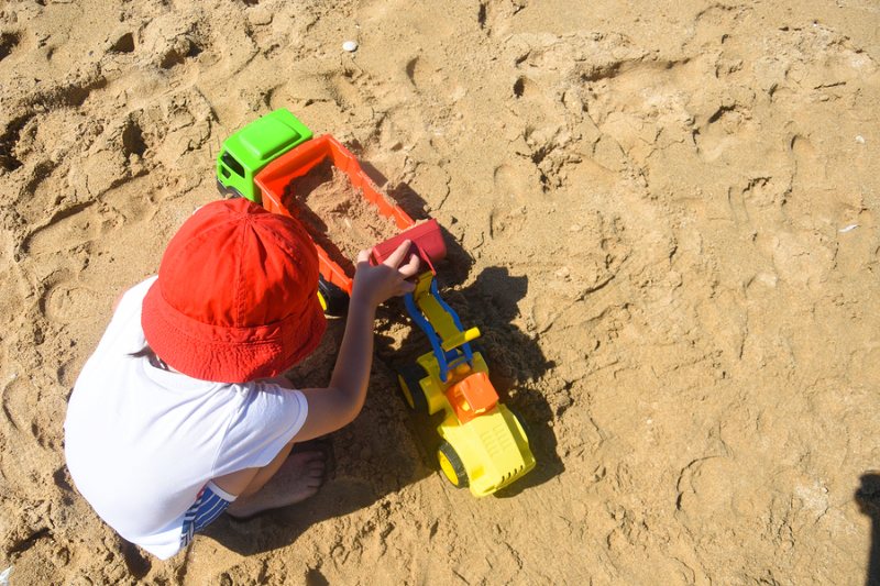 Young child playing in the sandpit with truck