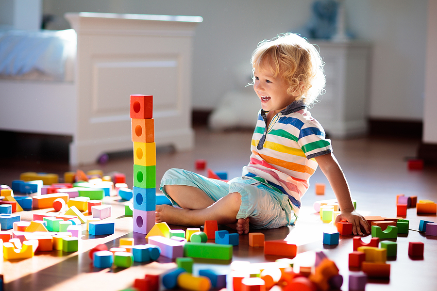 Child laughing as he looks at the tall tower he has built