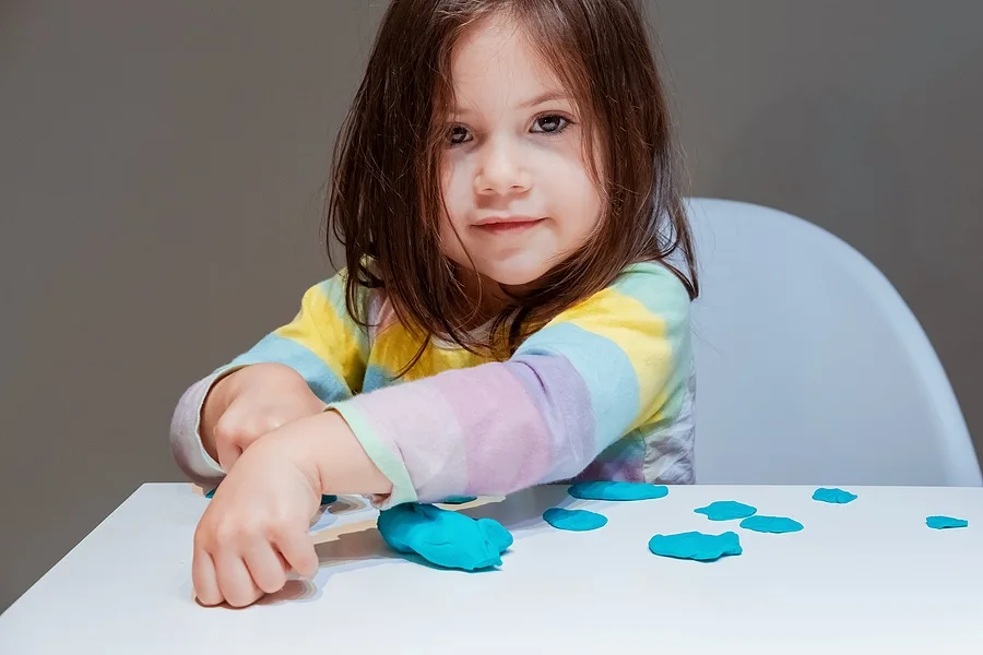 Little girl playing with blue playdough