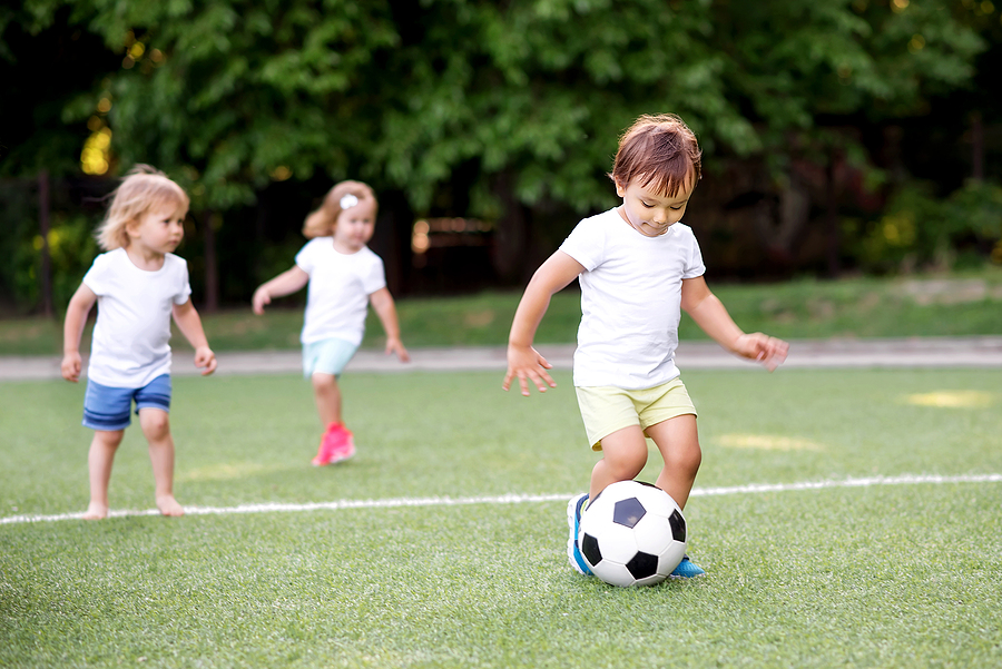 Preschoolers kicking a ball on a field