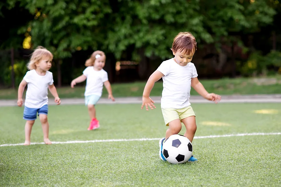 Preschoolers kicking a ball on a field