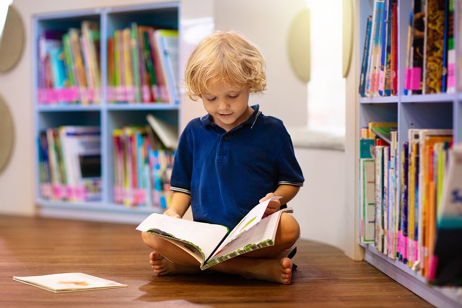 Young boy sitting on the floor, reading a book 