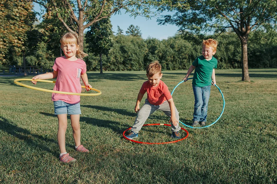 Children playing outside with hula hoops together.