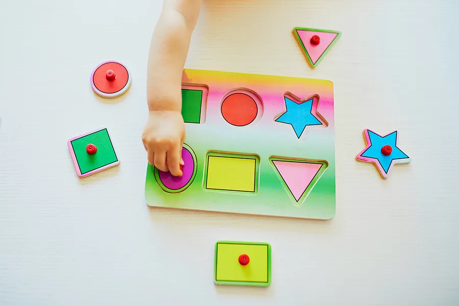 Child fitting the shapes of a peg puzzle.