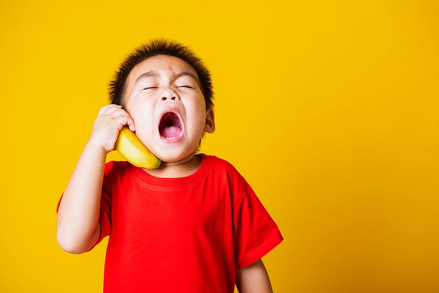 child using a banana as a phone