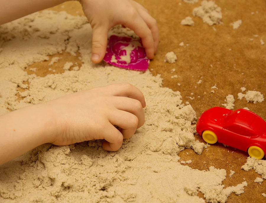 Child playing in the sand with toys