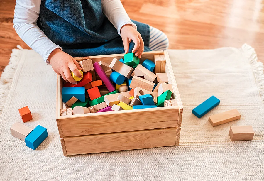 Child putting away blocks into wooden box