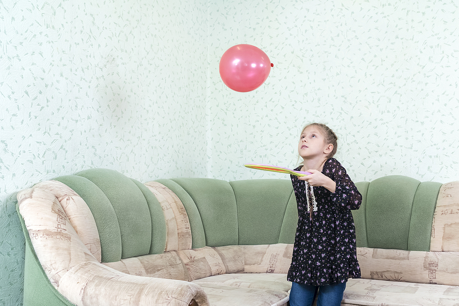 Child keeping a balloon up with a racket