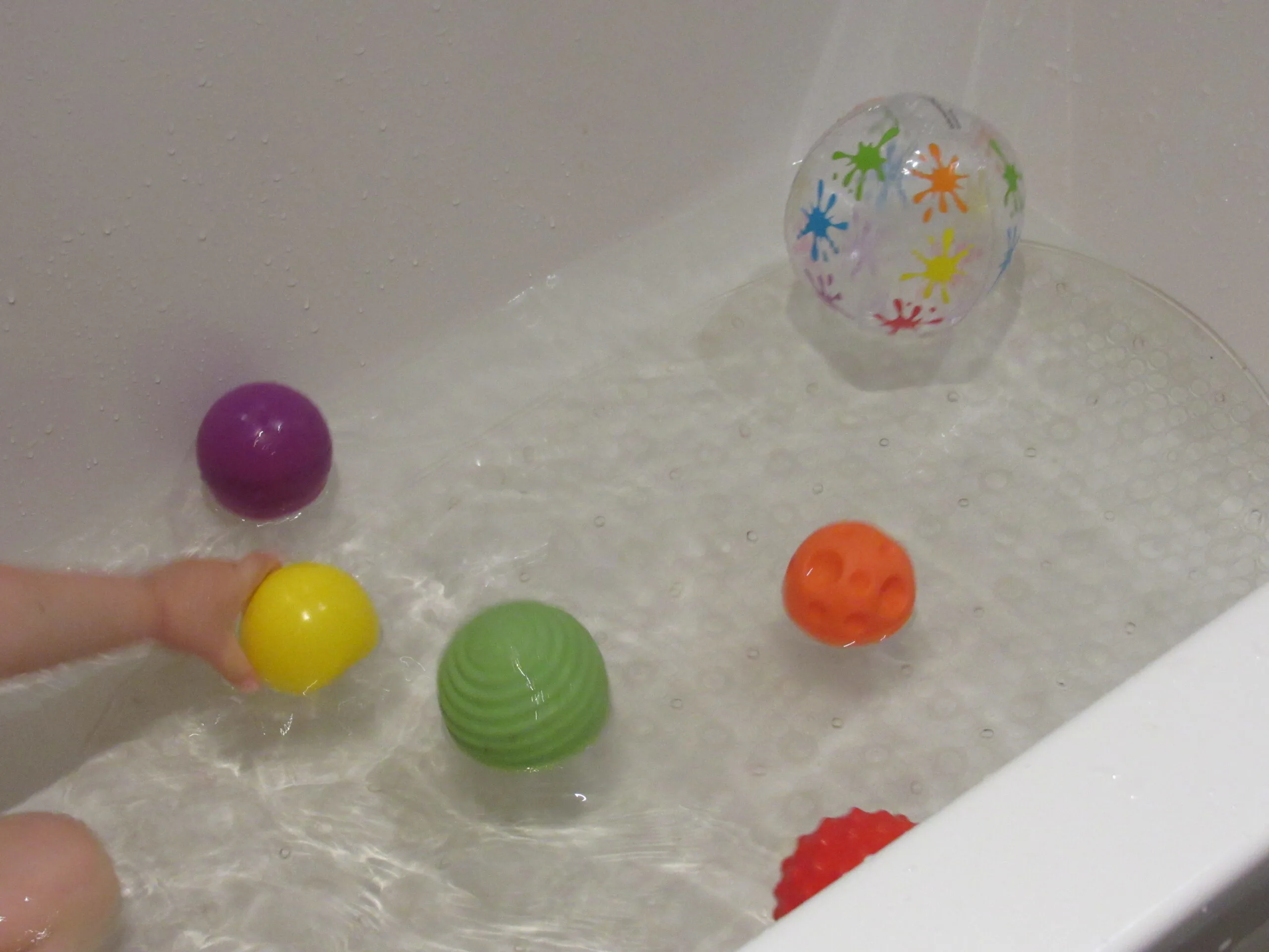 Child playing with balls in the bathtub