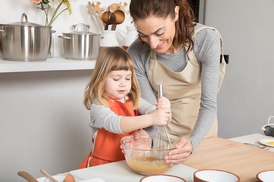 child mixing food with her mom