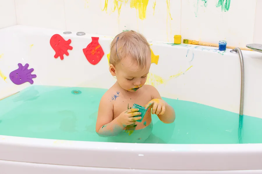 Kid painting with paint in the bathtub