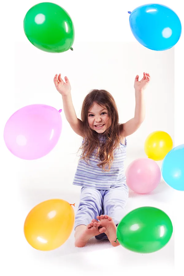 Little girl tossing balloons up in the air
