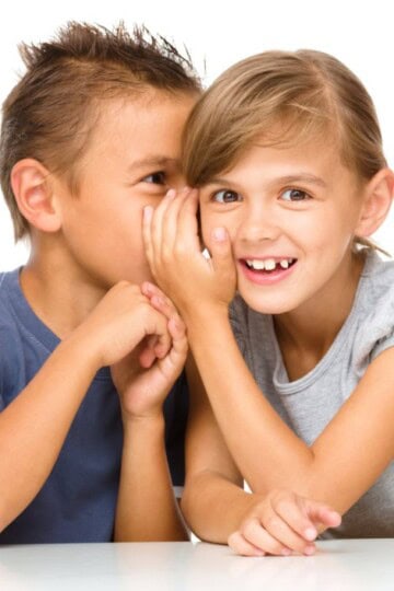 little boy whispering in girl's ear for a game