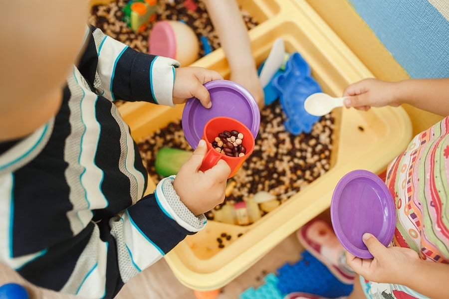 children playing with a sensory corn station