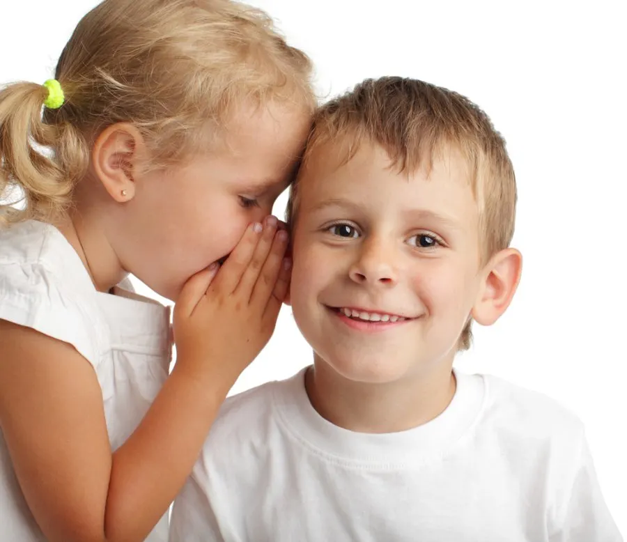 Little girl whispering in boys ear
