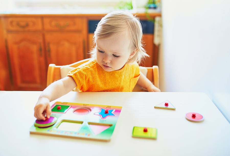 Young girl doing a peg puzzle.