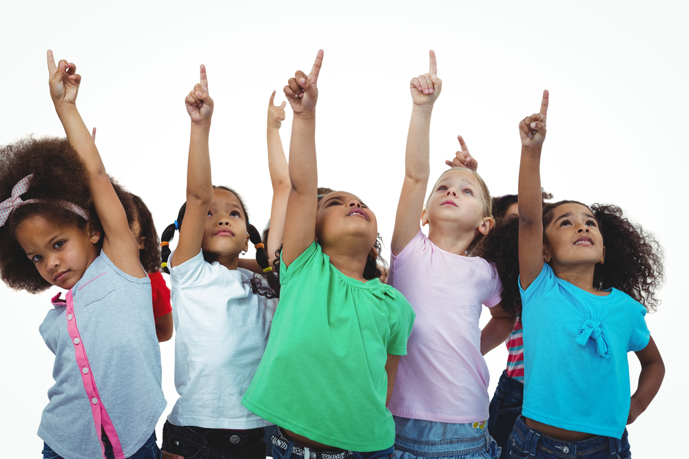 Group of primary school children pointing upwards