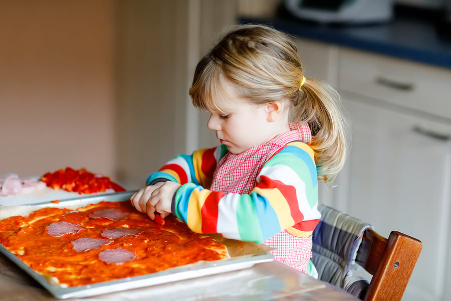 Little girl making pizzas in the kitchen