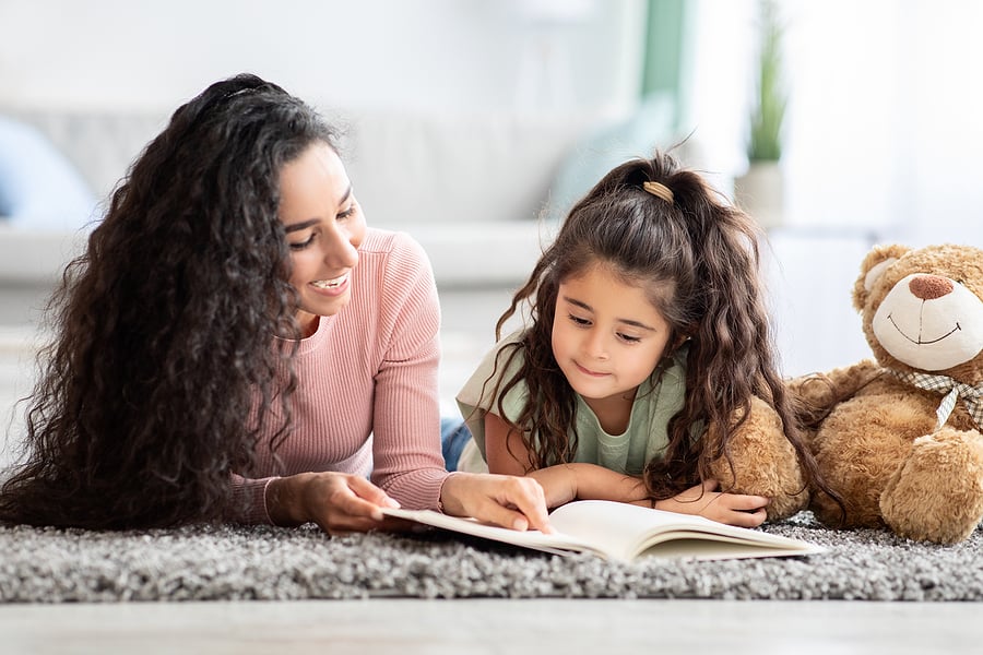 Mom and preschooler reading together on the carpet