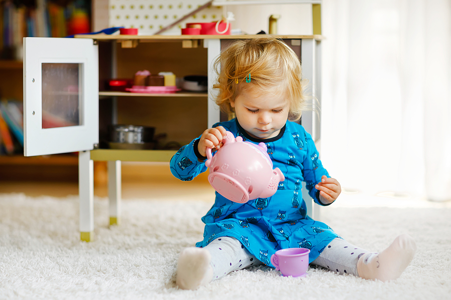 Little child playing with tea set and pouring a cup of tea.