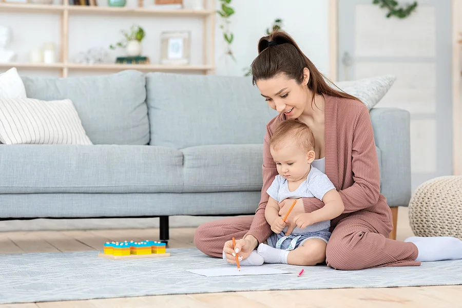 Mom and baby holding pencils and drawing on floor