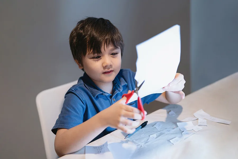 Preschooler cutting paper with scissors